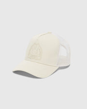 The MENS MELBOURNE GRAPHIC TRUCKER HAT by Psycho Bunny is light beige with a mesh back and curved brim. It features a subtle embossed bunny and crossbones on the front, complemented by an adjustable snap-back strap for the perfect fit.