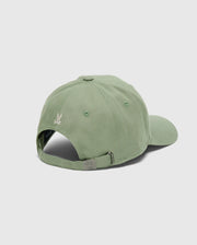 The Psycho Bunny MENS DESERT BASEBALL CAP - B6A549F200 is shown from the back, displaying a light green cotton material with an adjustable metal buckle strap. A small embroidered wordmark appears above the opening, all set against a plain gray background.