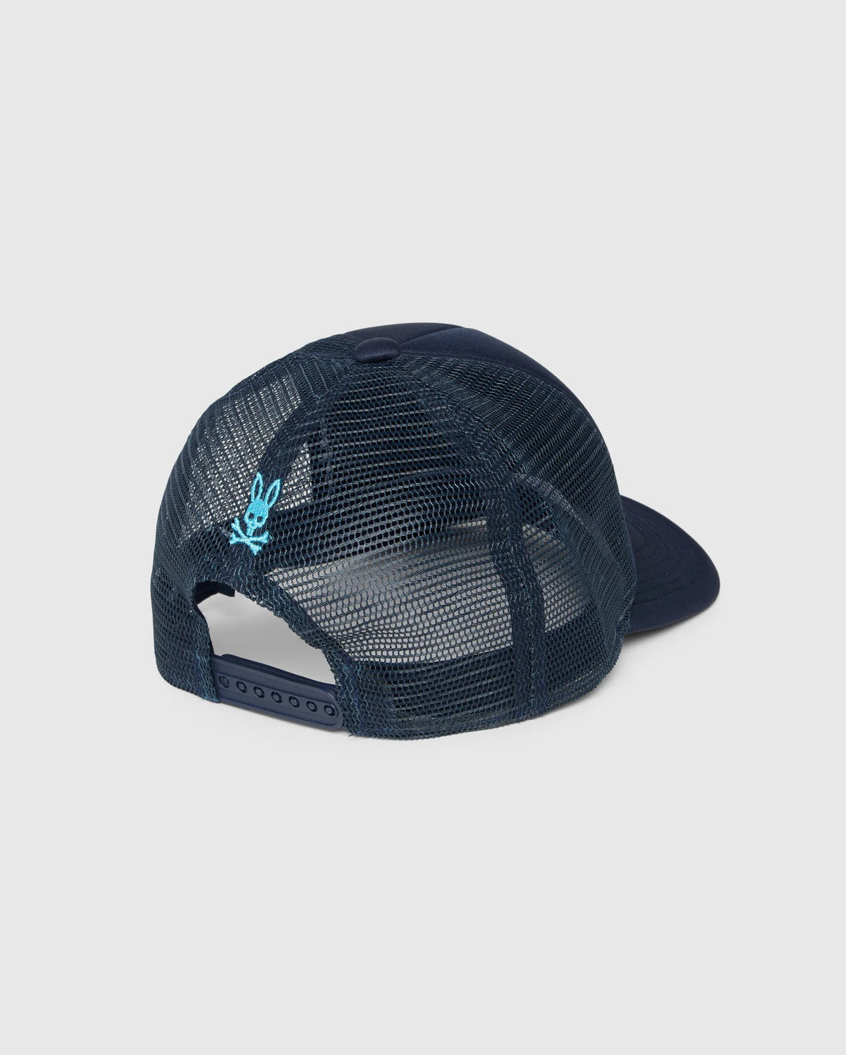 The image shows the back view of a navy-blue **MENS PARIS TRUCKER CAP - B6A591C200** by **Psycho Bunny**, featuring mesh paneling and a snapback closure. The mesh has a light blue embroidered detail near the closure with a subtle Bunny logo. The hat's crown and bill are solid navy blue.