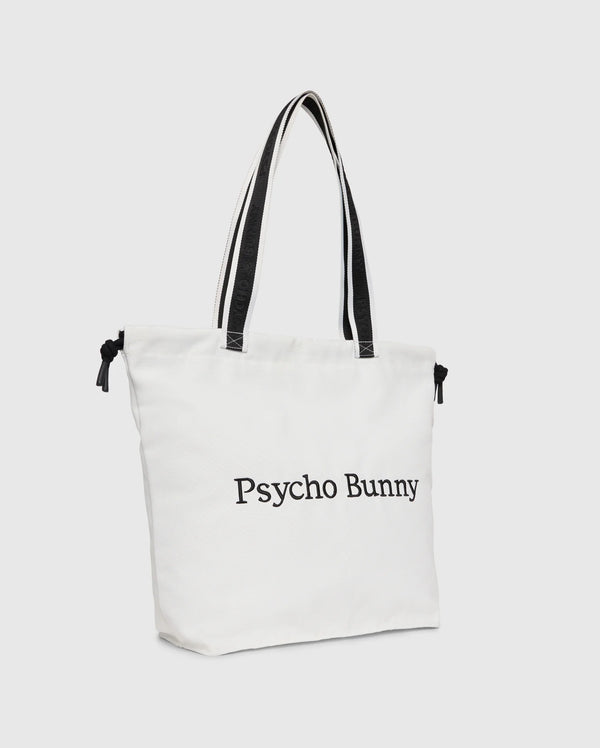 The "TENNIS TOTE - B6A596C200" by Psycho Bunny is a white canvas tote bag with black handles, featuring the text "Psycho Bunny" on the front and an embroidered logo for an elegant touch.