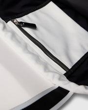 Close-up of the Psycho Bunny TENNIS TOTE - B6A596C200 shows a black and white garment with a zippered pocket. The contrast stitching between canvas sections highlights the design, while an embroidered logo adds elegance and seamlessly blends into its sophisticated style.