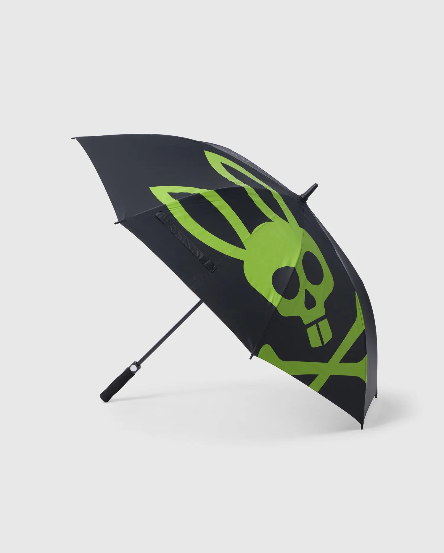 The GOLF UMBRELLA - B6A624C200 by Psycho Bunny features a large green graphic of a skull and bones, where the skull has bunny ears and buck teeth, on its black canopy. This reliable umbrella is open, revealing the full design with a black handle and partially visible shaft. Perfect for rain protection on or off the golf course.