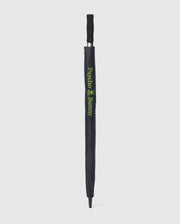 A black GOLF UMBRELLA - B6A624C200 with a matching handle is fully closed and sheathed. The sheath showcases green text and a small graphic, displaying "Psycho Bunny." Renowned for its dependable rain protection, this chic collapsible umbrella by Psycho Bunny stands out against the white background.