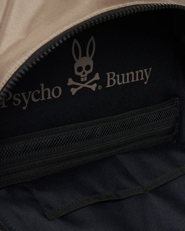 Close-up of the inside of an urban backpack featuring a black fabric lining with a zippered pocket. The lining has a logo with a bunny's head above crossbones and the text "Psycho Bunny." The zipper of the pocket is partially visible, complemented by a padded laptop compartment for added style. This is the MENS DOME BACKPACK - B6A628Z1BP by Psycho Bunny.