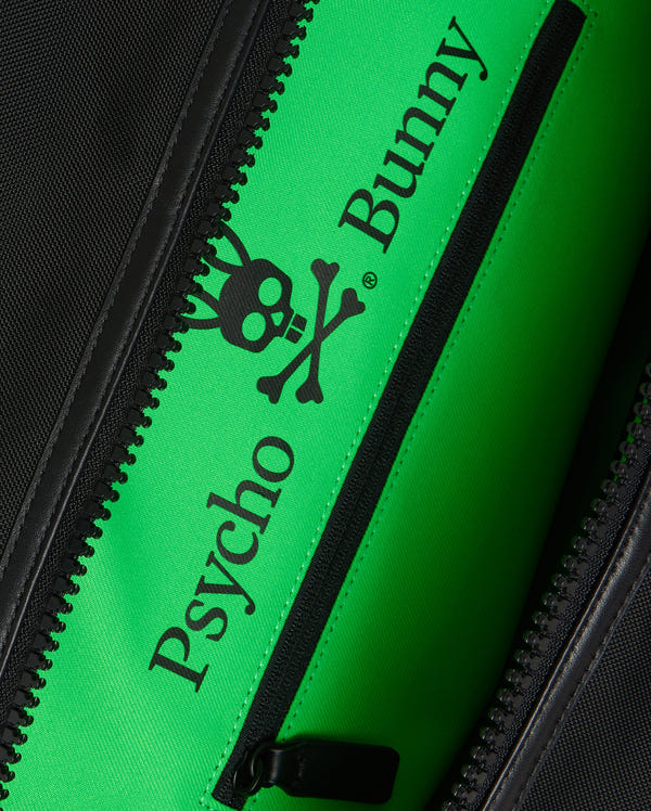 Close-up image of a zippered pocket inside the MENS WEEKENDER BAG - B6A629Z1BG with a bright green lining. The lining features the text "Psycho Bunny" in black letters along with a black logo of a bunny skull and crossbones.