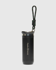 The Psycho Bunny MENS TRAVEL COFFEE MUG (B6A634F200) is an eco-friendly black stainless steel tumbler with a lid, featuring the iconic logo. It includes a black and green looped carabiner handle on top, set against a plain white background, perfect for hydration on the go.