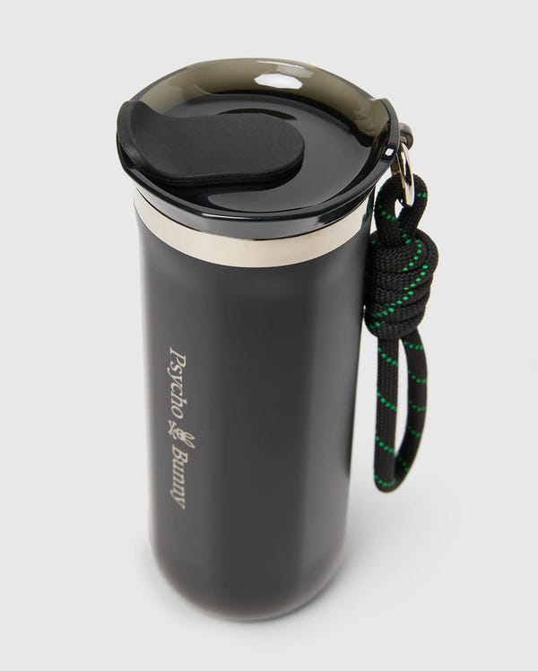 The MENS TRAVEL COFFEE MUG - B6A634F200 by Psycho Bunny is a black travel mug with an eco-friendly stainless steel build, featuring a screw-on lid, carrying handle, and the "Psycho Bunny" logo for stylish hydration.