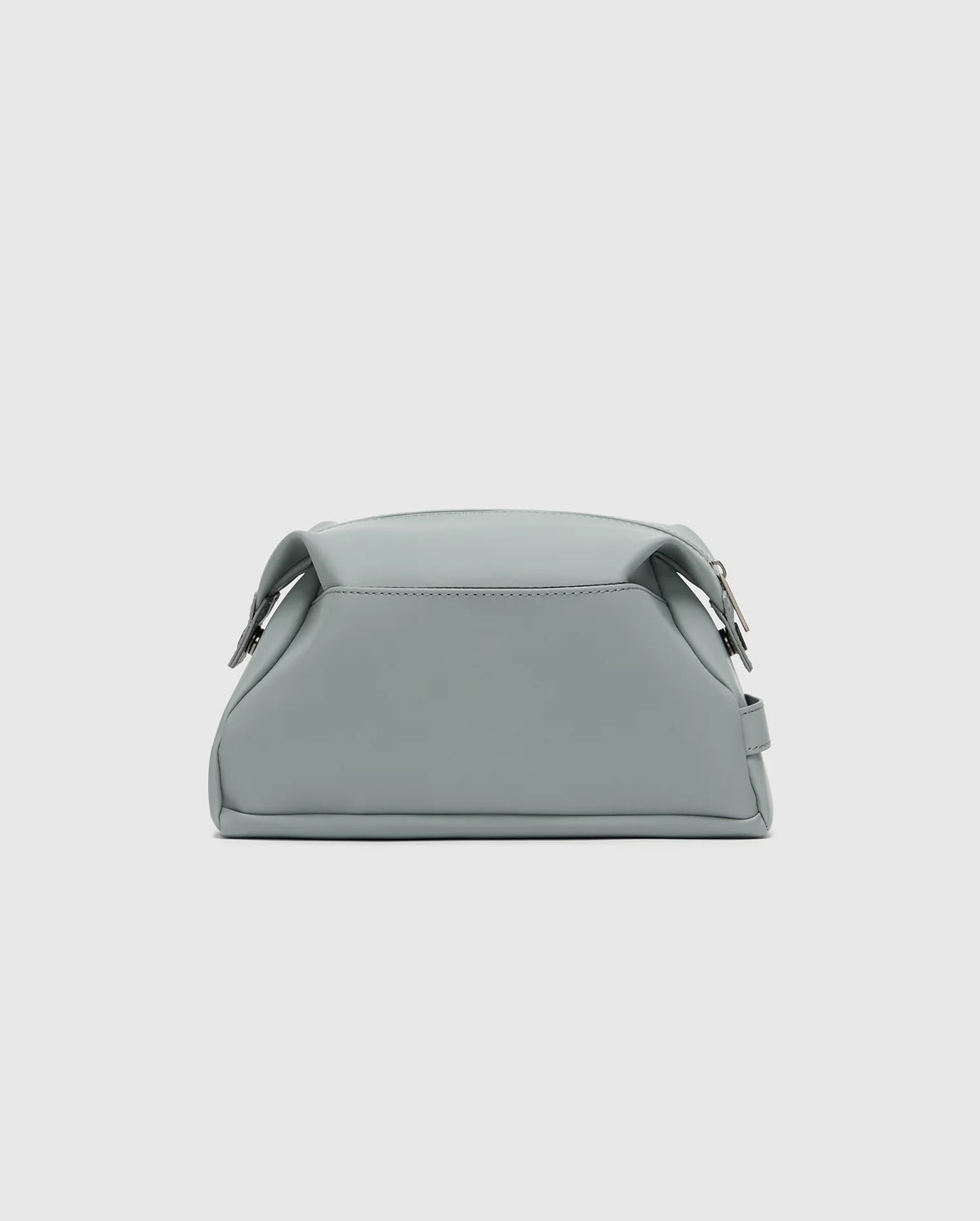 The Psycho Bunny MENS TOILETRY KIT - B6A636F200 is a small, minimalist mint green polyester bag with a sleek finish, structured shape, two side buckles, and a top handle to organize essentials on the go against a light gray background.