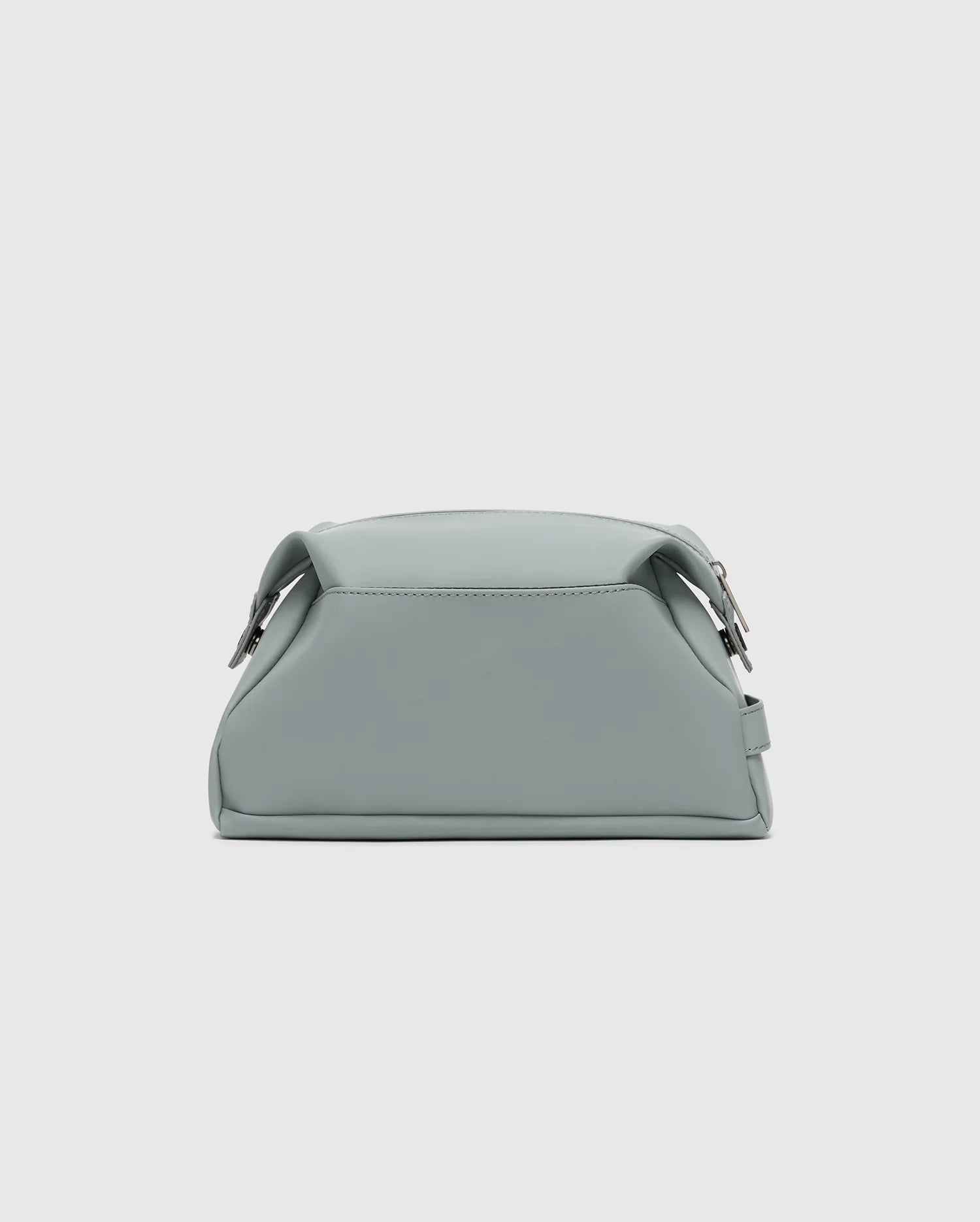 The Psycho Bunny MENS TOILETRY KIT - B6A636F200 is a small, minimalist mint green polyester bag with a sleek finish, structured shape, two side buckles, and a top handle to organize essentials on the go against a light gray background.