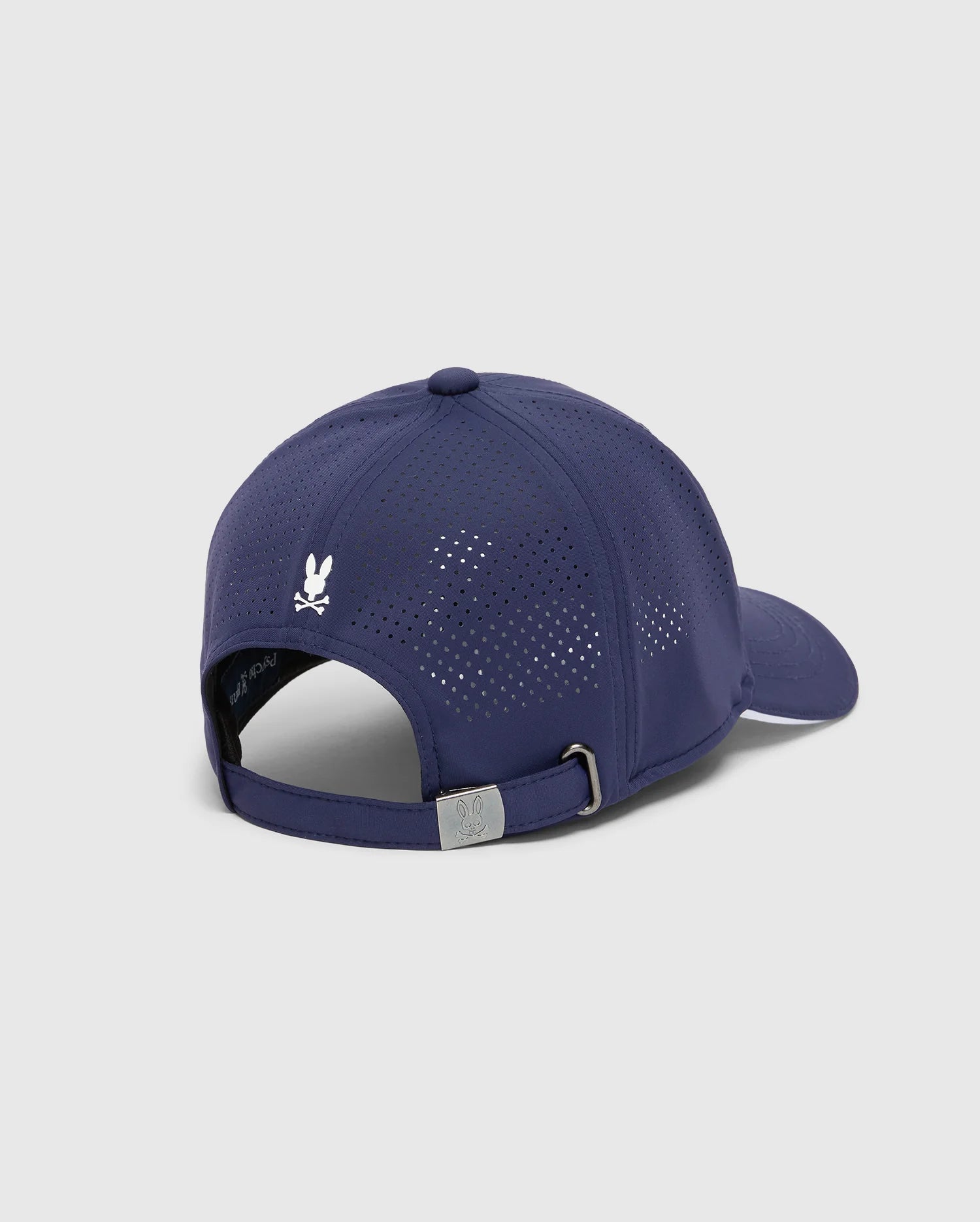 The MENS DENIS SPORT CAP - B6A642F200 by Psycho Bunny is a dark blue cap with a sporty, practical design, crafted from lightweight cotton. It features ventilation holes, an adjustable strap with a silver buckle, and a small white logo on the back against a light gray background.
