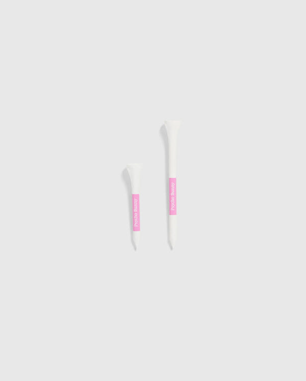 The image features two white tubes set against a light gray background, each with a pink label. The smaller tube is positioned on the left and is decorated with Psycho Bunny's 75 PACK GOLF TEES - B6A659C200, accented by bunny-themed designs. The larger tube is on the right, ideal for those looking for whimsical golf accessories from the Psycho Bunny brand.