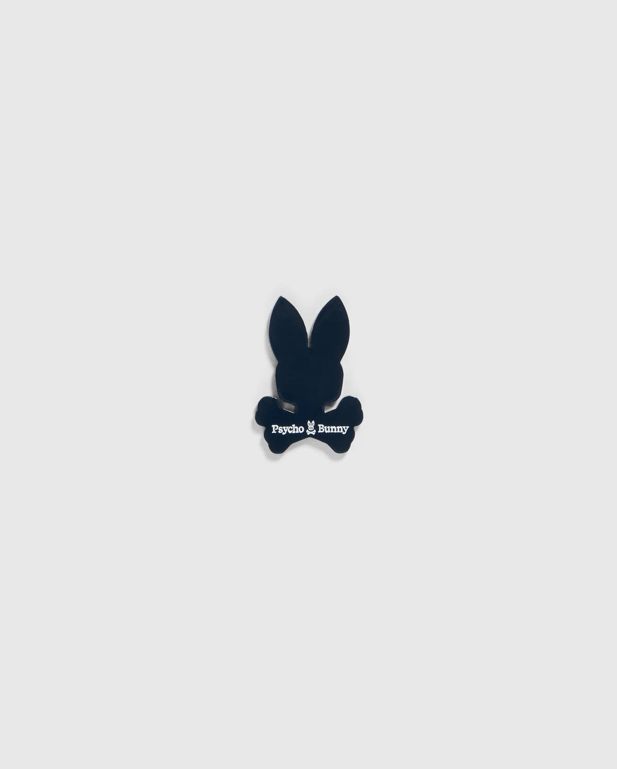 A small black silhouette of a bunny head with long ears and crossbones underneath, featuring the text "Psycho Bunny" in white below the head and above the crossbones, designed as an edgy BALL MARKER - B6A698C200 perfect for any golfer's collection by Psycho Bunny.