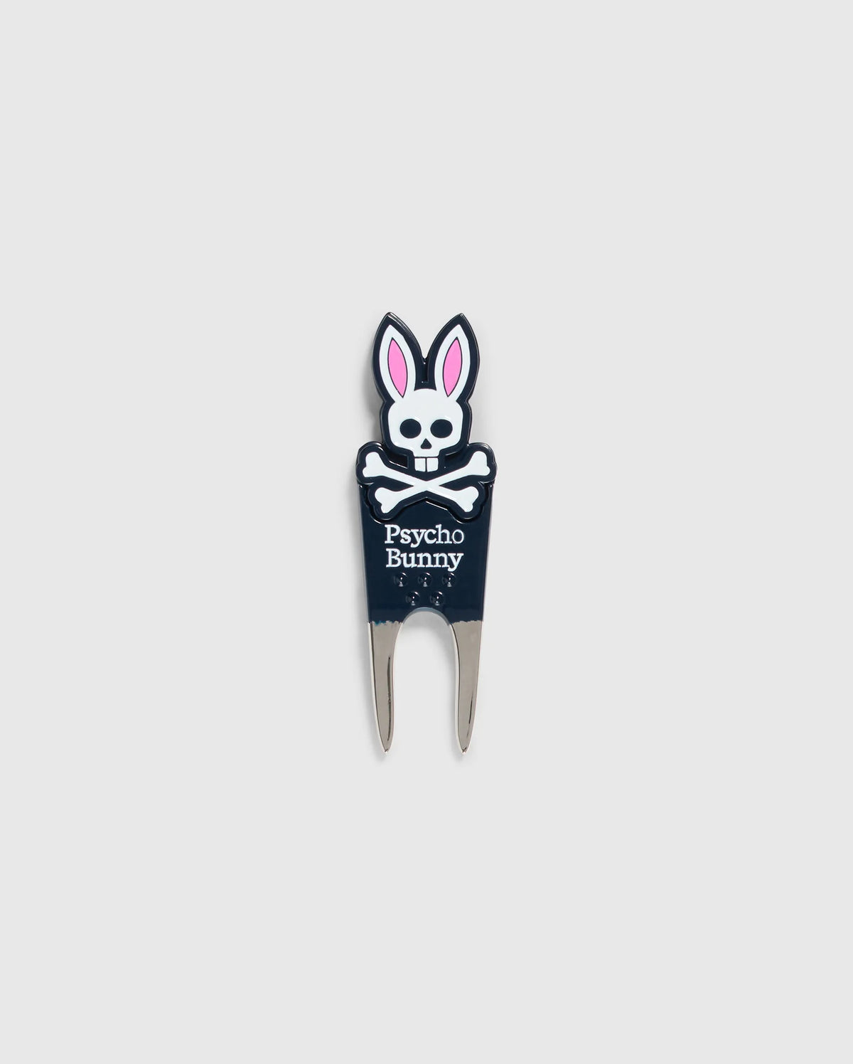 Image of a DIVOT TOOL - B6A699C200 from Psycho Bunny with a design featuring a skull with bunny ears and the text "Psycho Bunny" underneath. The tool has two prongs at the bottom, and the skull and ears are in black, white, and pink. A perfect addition to golf gifts, this tool also comes with a magnetic ball marker. The background is plain gray.