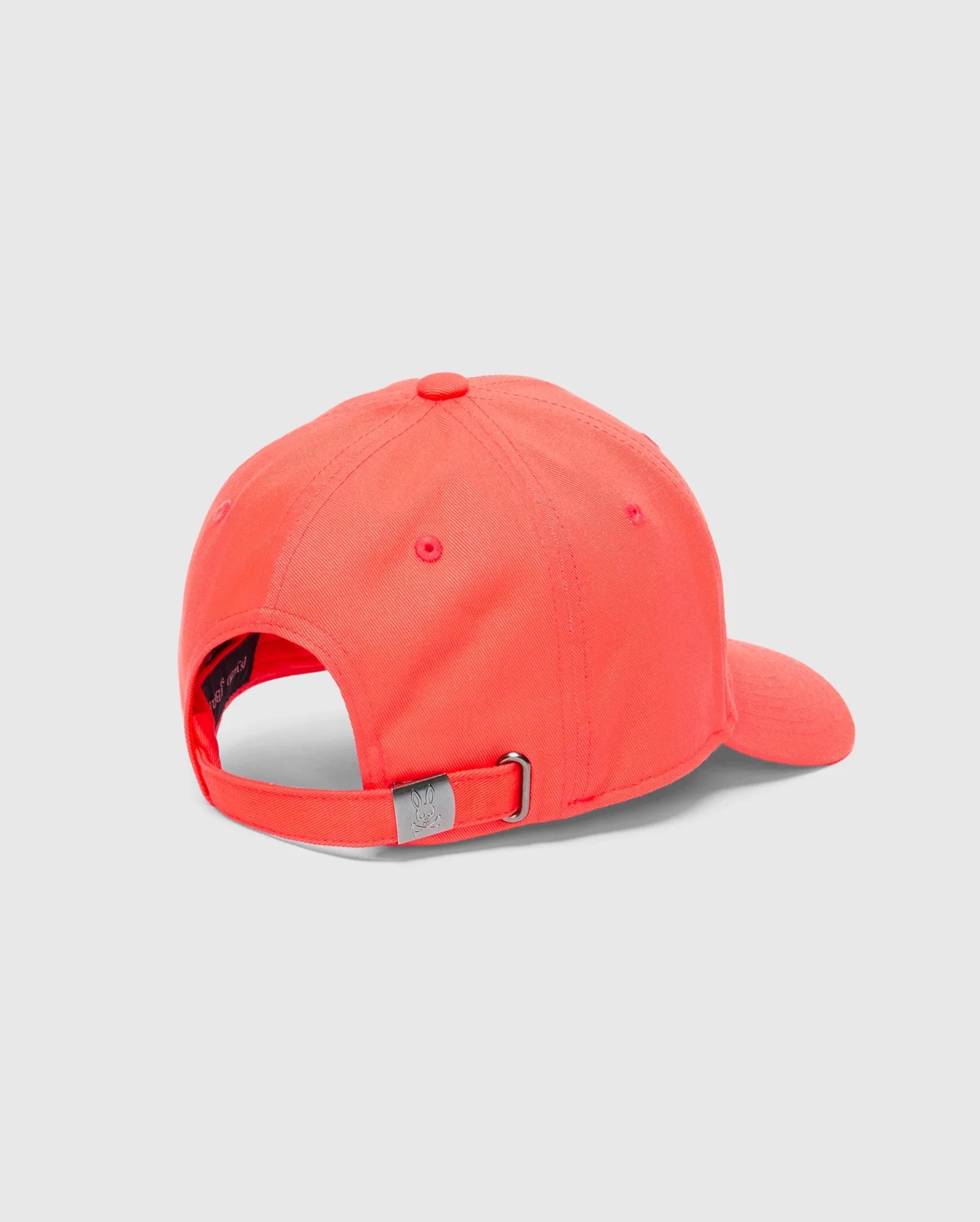 The Psycho Bunny Men's Classic Baseball Cap (B6A816F200) in bright coral, made from cotton twill, is displayed from the back with an adjustable strap and metal clasp for a perfect fit. It includes ventilation eyelets and a curved brim against a light gray background.