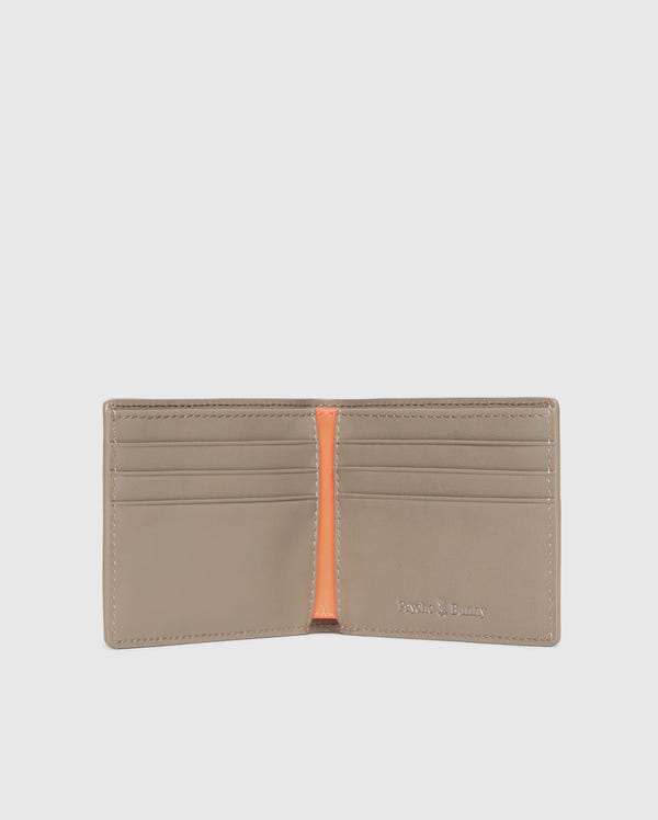 A luxury Psycho Bunny men's leather wallet is open, showcasing multiple card slots and an orange interior accent. The brand name is embossed in silver on the bottom right corner. The plain light gray background highlights the elegance of this premium accessory.