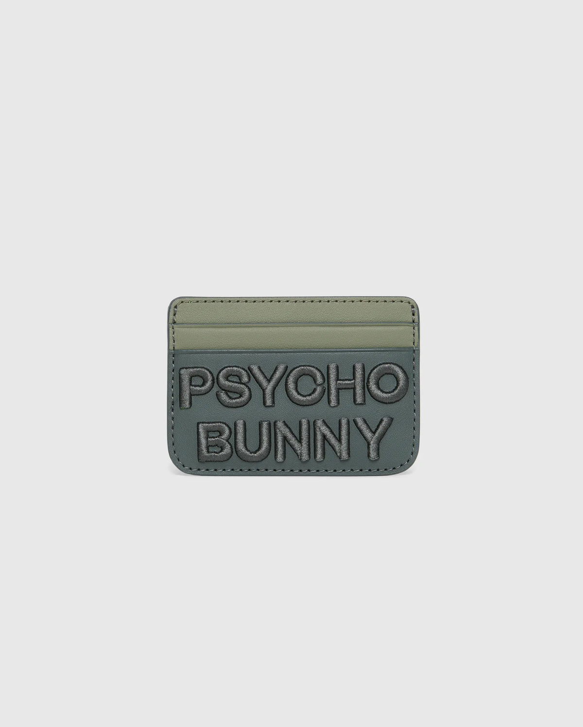 The MENS WORDMARK LEATHER CARD CASE - B6A869D200 by Psycho Bunny is a green, minimalist leather card holder made from durable shell pebble leather. It features two card slots, "PSYCHO BUNNY" embossed on the front with raised text, and a soft matte finish.