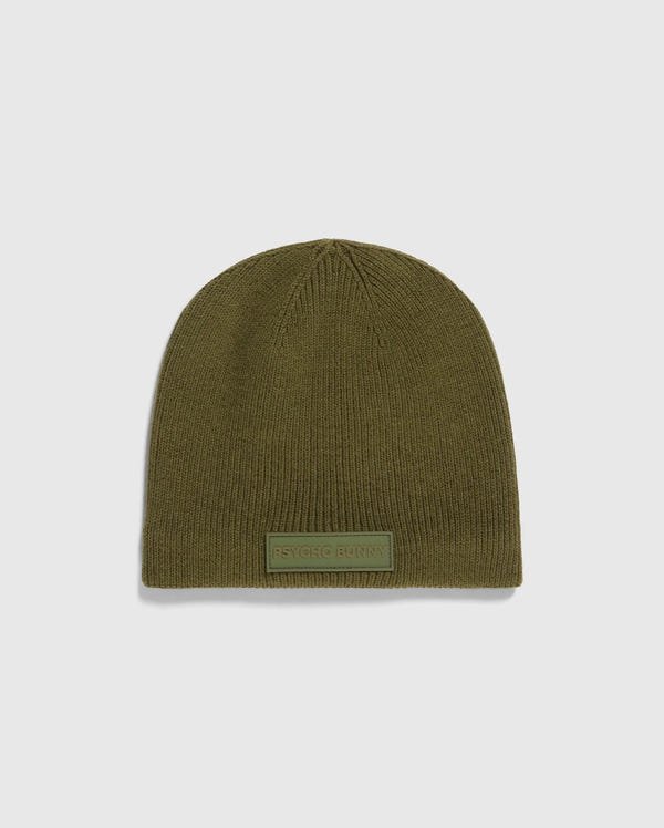 The MENS SPORT BEANIE - B6A874D200 by Psycho Bunny is a premium olive green knitted hat made from merino wool, featuring a small rectangular "Psycho Bunny" patch on the front. It is showcased against a light gray background, emphasizing its high-performance quality.