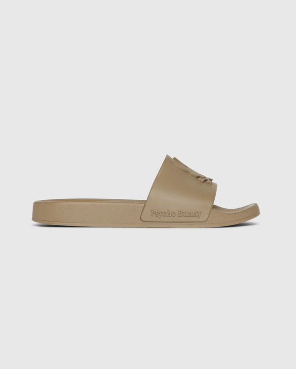 A single beige pool slide with a broad strap featuring the text "Psycho Bunny" embossed on it, presented against a white background.