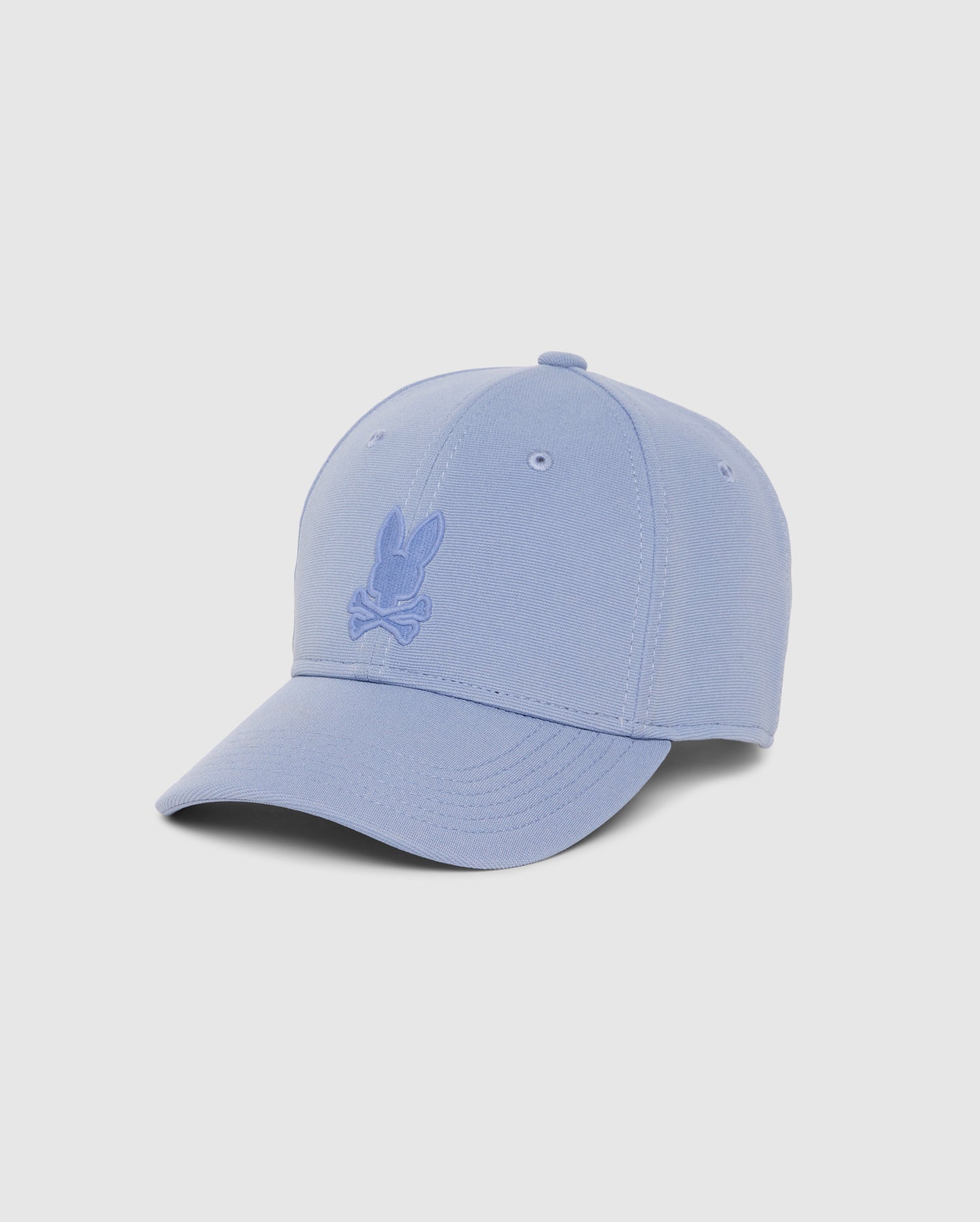 Introducing the Psycho Bunny MENS JAMES PREMIUM BASEBALL CAP in light blue, featuring knit twill fabric. This cap showcases a tonal embroidered bunny head logo with crossed bones, a slightly curved brim, and visible stitching against a plain white background.