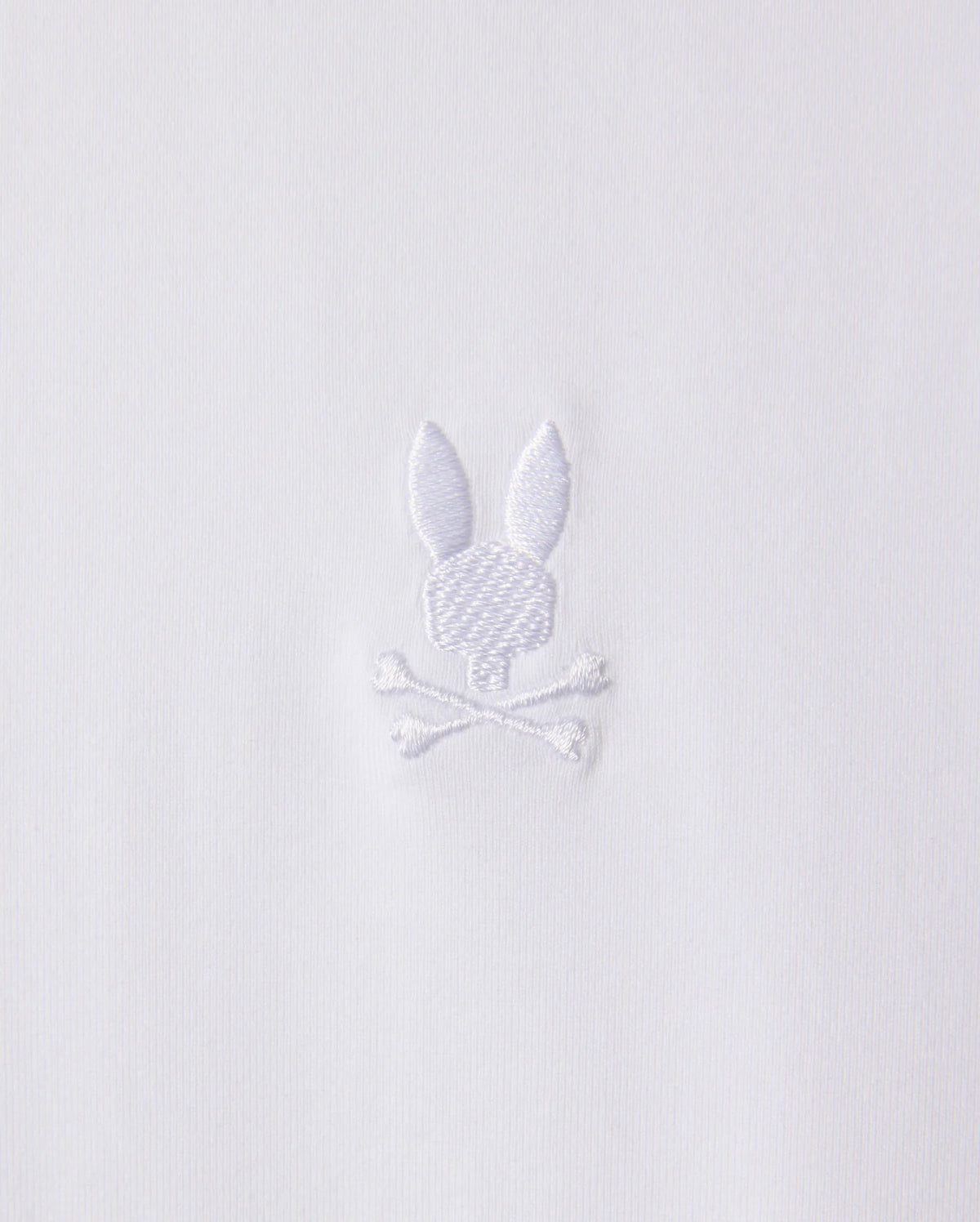 The MENS ARTHUR JERSEY SHIRT - B6C748D200 by Psycho Bunny is made from white jersey fabric and features a discreet embroidered design of a bunny head atop two crossed bones.