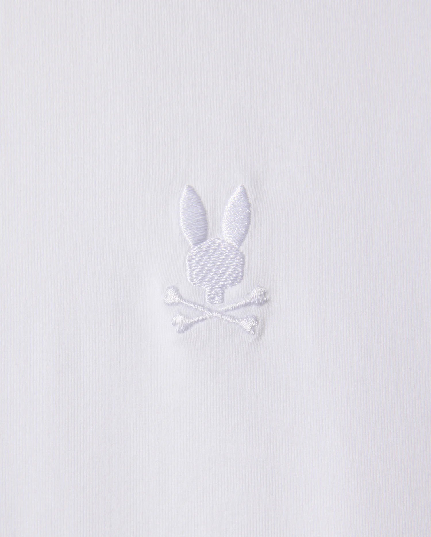 The MENS ARTHUR JERSEY SHIRT - B6C748D200 by Psycho Bunny is made from white jersey fabric and features a discreet embroidered design of a bunny head atop two crossed bones.