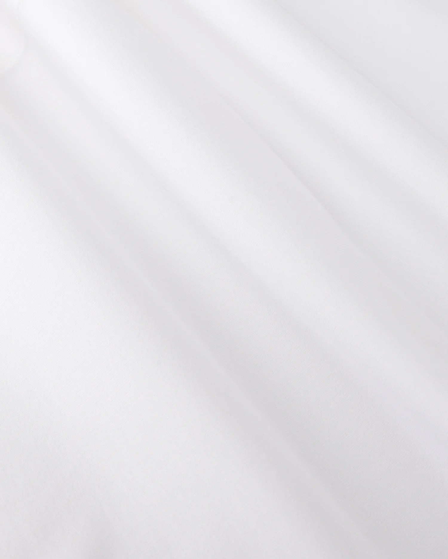 Close-up of smooth, white jersey fabric with gentle shadows forming soft folds. The texture appears soft and slightly matte, reminiscent of the MENS ARTHUR JERSEY SHIRT - B6C748D200 by Psycho Bunny, evoking a sense of lightness and simplicity.