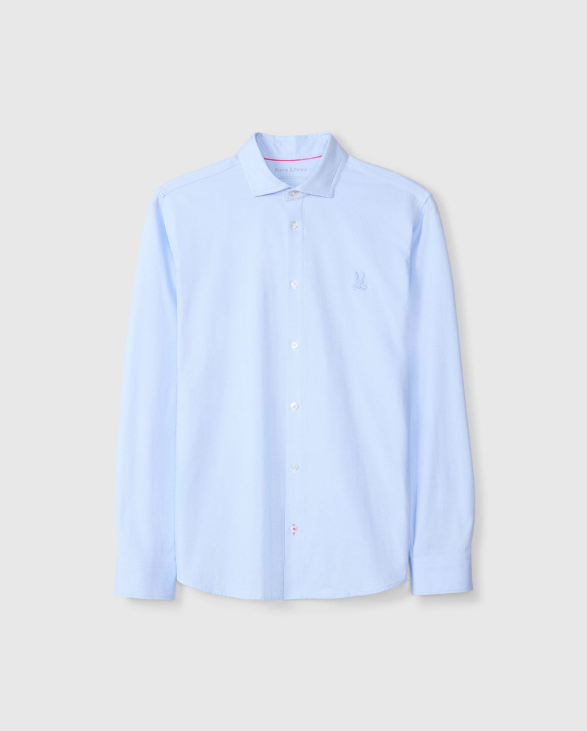 The Psycho Bunny MENS BRENDAN JERSEY SHIRT - B6C749D200 is a light blue button-up shirt with long sleeves and a crisp collar, featuring an embroidered chest Bunny logo. Made from soft Pima cotton, the shirt is neatly pressed and displayed against a plain background.