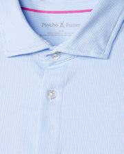 Close-up of the MENS BROOK STRIPED JERSEY SHIRT - B6C750D200 from Psycho Bunny, showcasing its light blue and white striped design, crafted from soft Pima cotton with a collar and two buttons. The inside label bears the "Psycho Bunny" name and a small logo, making it not just any shirt but a comfortable option perfect for any occasion.