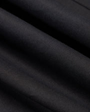 A close-up of Psycho Bunny's MENS JARED COTTON MODAL SHIRT in dark gray or black highlights a premium cotton fabric with subtle diagonal textures, folded slightly to create gentle waves and shadows, ideal for crafting its smooth and soft appearance.