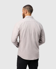 A man with short hair is seen from behind in a light gray Psycho Bunny MENS JARED COTTON MODAL SHIRT (B6C774D200) paired with black cargo pants against a neutral background.