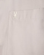 Close-up of a beige pocket on the Psycho Bunny MENS JARED COTTON MODAL SHIRT - B6C774D200, highlighting intricate stitching and an embroidered rabbit head with crossed bones.