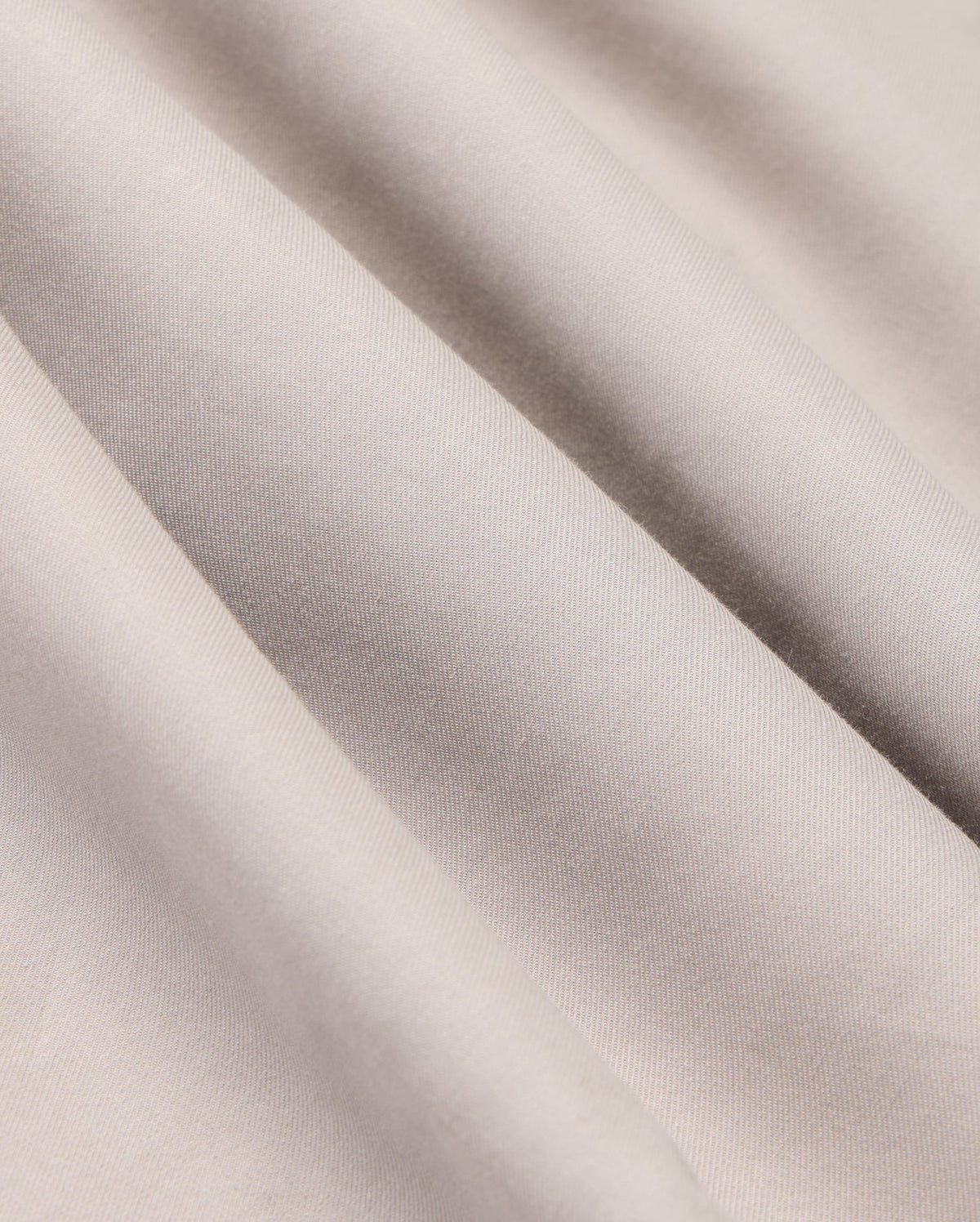 The MENS JARED COTTON MODAL SHIRT by Psycho Bunny features light grey, textured fabric with soft diagonal folds and subtle shadows, highlighting its smooth, slightly shiny surface reminiscent of a premium cotton shirt.