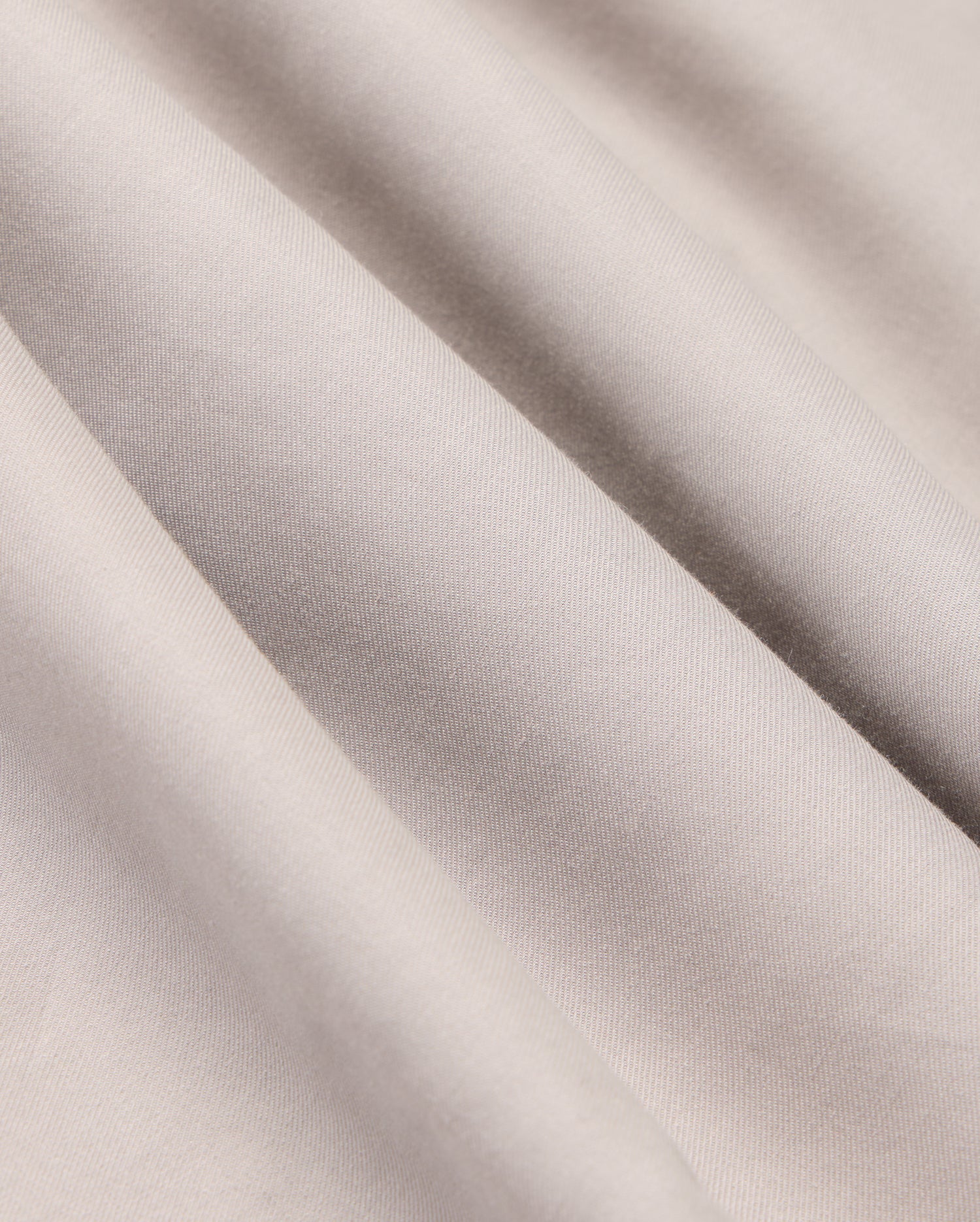 The MENS JARED COTTON MODAL SHIRT by Psycho Bunny features light grey, textured fabric with soft diagonal folds and subtle shadows, highlighting its smooth, slightly shiny surface reminiscent of a premium cotton shirt.