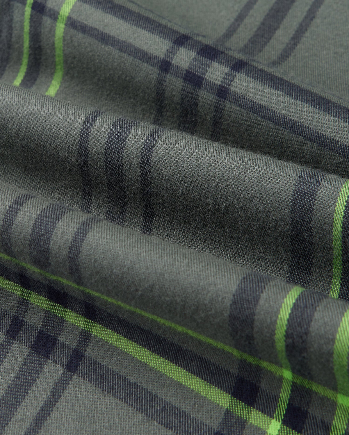 Close-up of the Psycho Bunny MENS HAYES PLAID SHIRT (B6C842D200) highlighting its premium design in green plaid fabric featuring dark and light lime green stripes. The soft Pima cotton provides visible texture and subtle folds, making it perfect for a stylish men's plaid shirt look.
