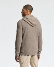 A man stands facing away, wearing the Psycho Bunny MENS LEVAN WAFFLE HOODED SWEATER and beige pants against a plain white background.