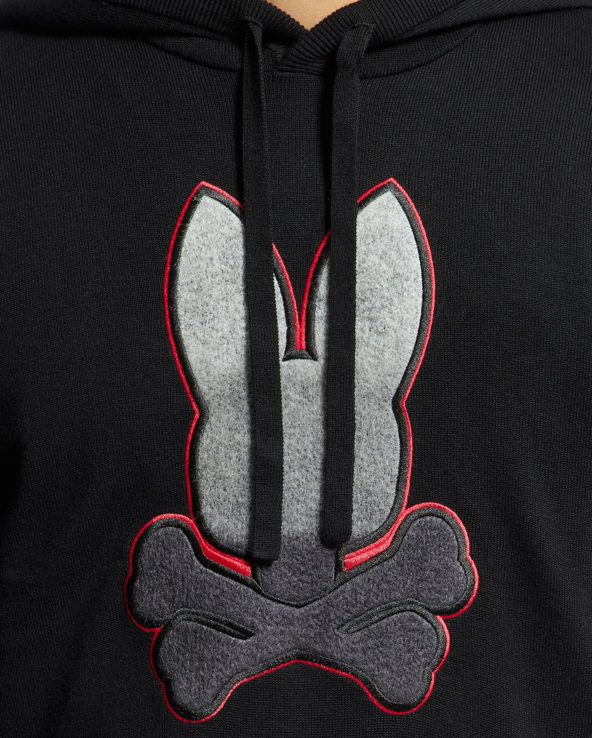 The MENS BULDER HOODED SWEATER - B6E261E200 by Psycho Bunny boasts a striking design featuring a large gray and red outlined bunny head above crossed bones. Made from soft Supima cotton, it includes front-hanging drawstrings that enhance its sleek appearance.