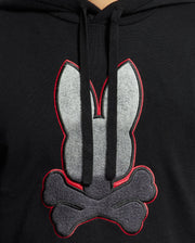 The MENS BULDER HOODED SWEATER - B6E261E200 by Psycho Bunny boasts a striking design featuring a large gray and red outlined bunny head above crossed bones. Made from soft Supima cotton, it includes front-hanging drawstrings that enhance its sleek appearance.