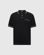 The Psycho Bunny MENS LONGFORD FINE KNIT POLO (B6E500F200) is a black short-sleeved shirt made of fine-knit cotton with white trim on the collar, sleeves, and pocket edge. It features an embroidered chest pocket on the left side and a three-button placket against a plain light gray background.