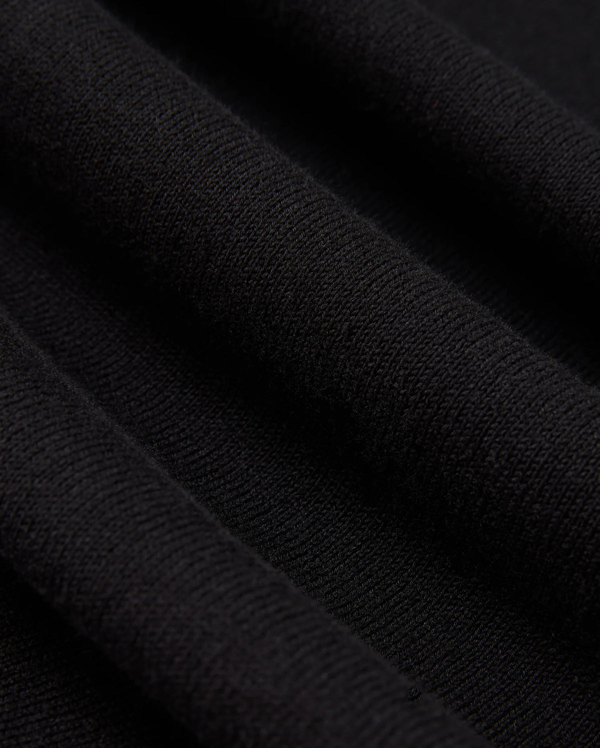 A detailed view of the Psycho Bunny MENS BELMORE EXTRA FINE COTTON SWEATER - B6E832D200 showcases the intricate ribbed texture formed by parallel lines in its extrafine cotton knit. The lighting accentuates the sweater's high-quality stitching, enhancing its soft and luxurious look.