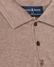 Close-up of a beige polo for men, crafted from merino wool, featuring three buttons and a visible label that reads "Psycho Bunny," along with size "M." The fabric appears soft and textured. This is the MENS BRADSHAW POLO SWEATER - B6E835D200.