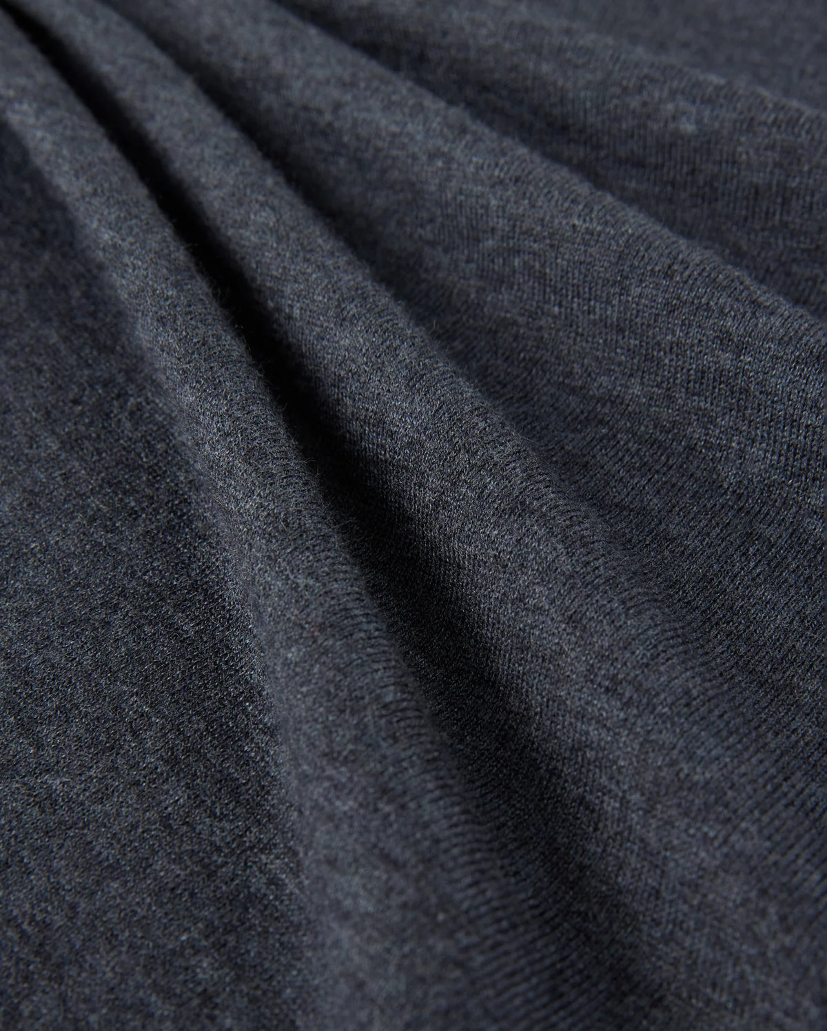 Close-up of the Psycho Bunny Men's Bradshaw Polo Sweater - B6E835D200, showcasing its dark gray fabric with a soft, smooth texture and gentle folds. The surface appears slightly fuzzy, indicating that this premium merino wool material is warm and comfortable, perfect for a luxury polo sweater.