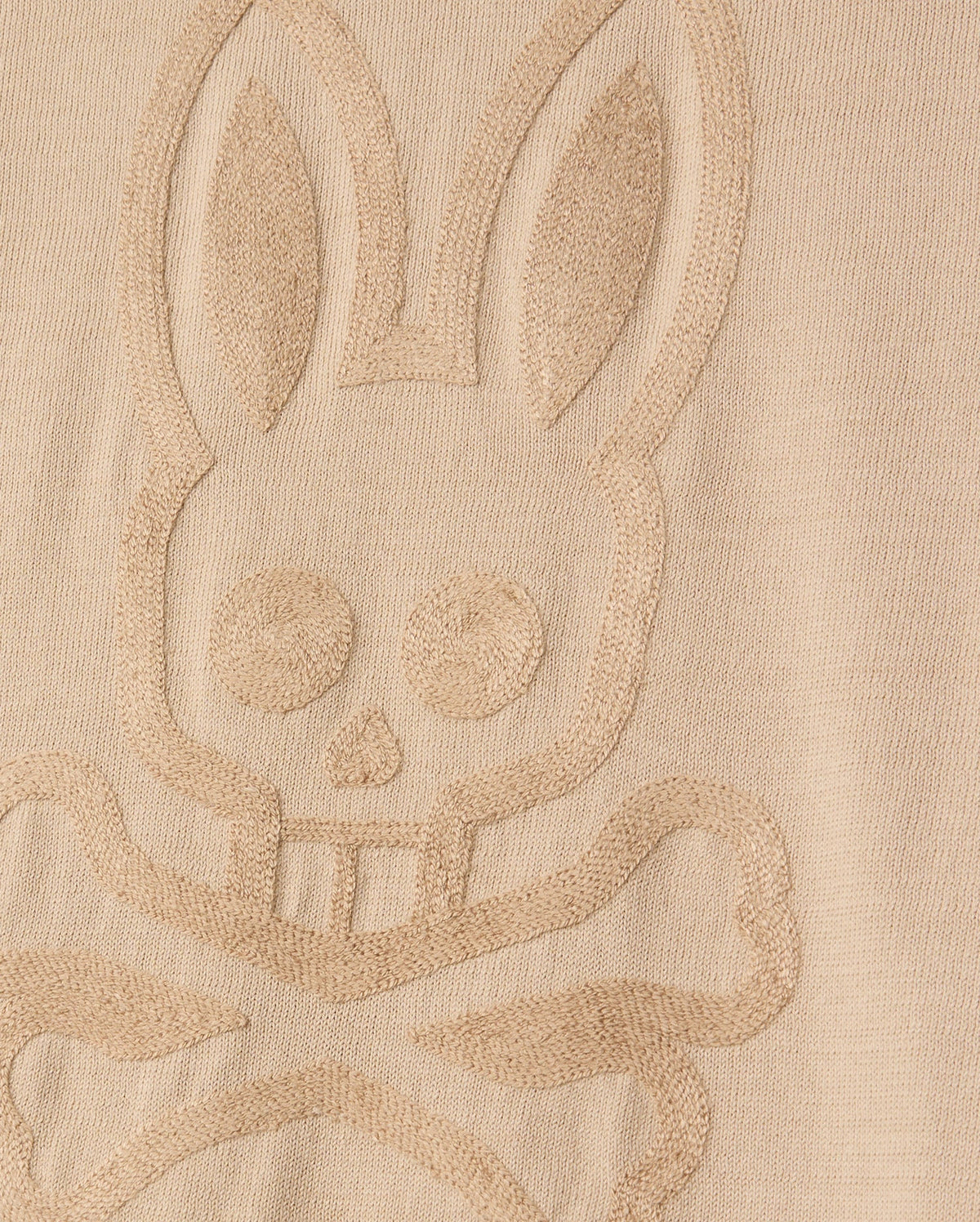 The MENS CORY CHAINSTITCH COTTON SWEATER by Psycho Bunny features a bunny skull and crossbones in an embossed design on its lightweight cotton fabric. The texture emphasizes the raised pattern against the smooth backdrop, similar to chainstitch embroidery.