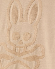 The MENS CORY CHAINSTITCH COTTON SWEATER by Psycho Bunny features a bunny skull and crossbones in an embossed design on its lightweight cotton fabric. The texture emphasizes the raised pattern against the smooth backdrop, similar to chainstitch embroidery.
