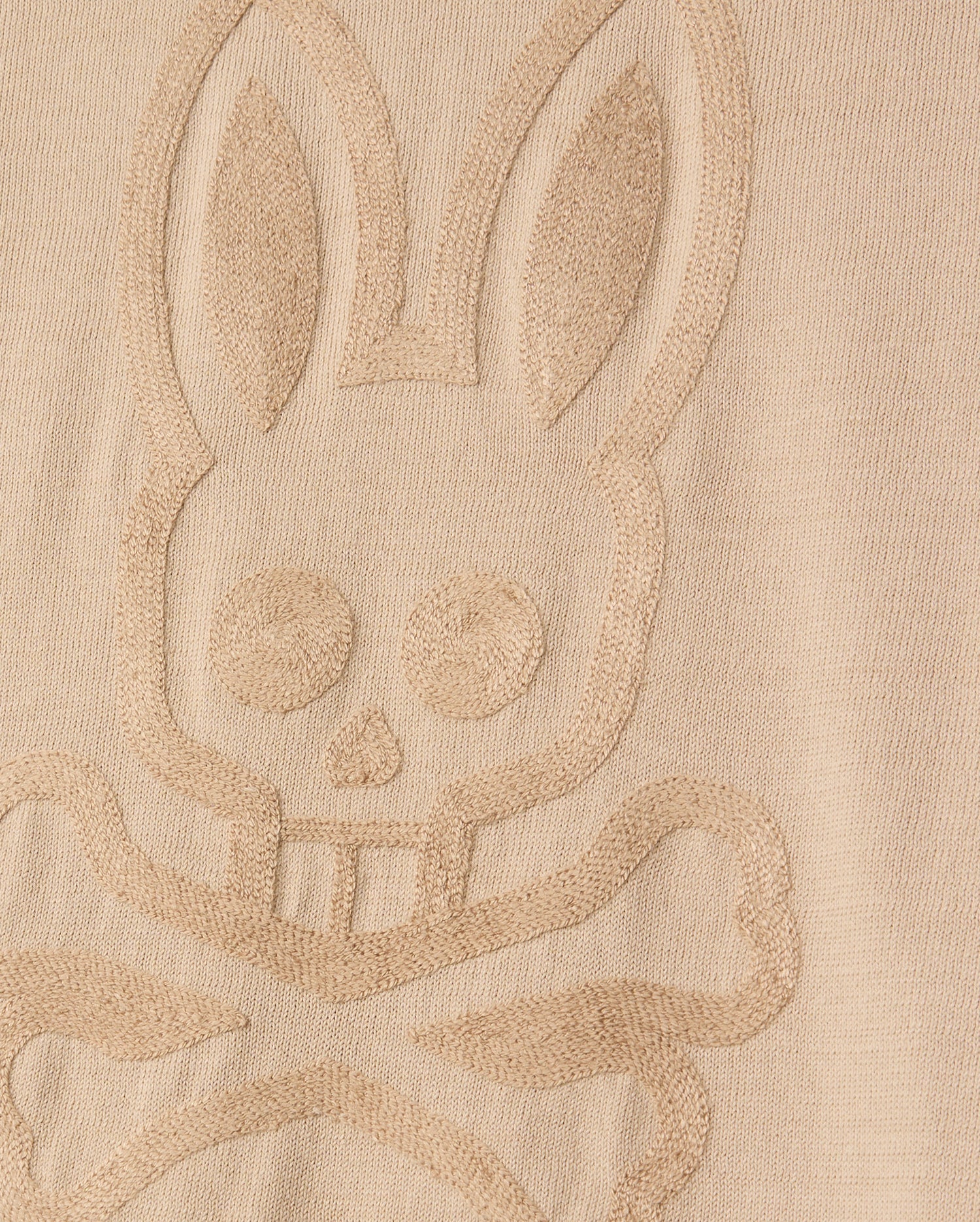 The MENS CORY CHAINSTITCH COTTON SWEATER by Psycho Bunny features a bunny skull and crossbones in an embossed design on its lightweight cotton fabric. The texture emphasizes the raised pattern against the smooth backdrop, similar to chainstitch embroidery.