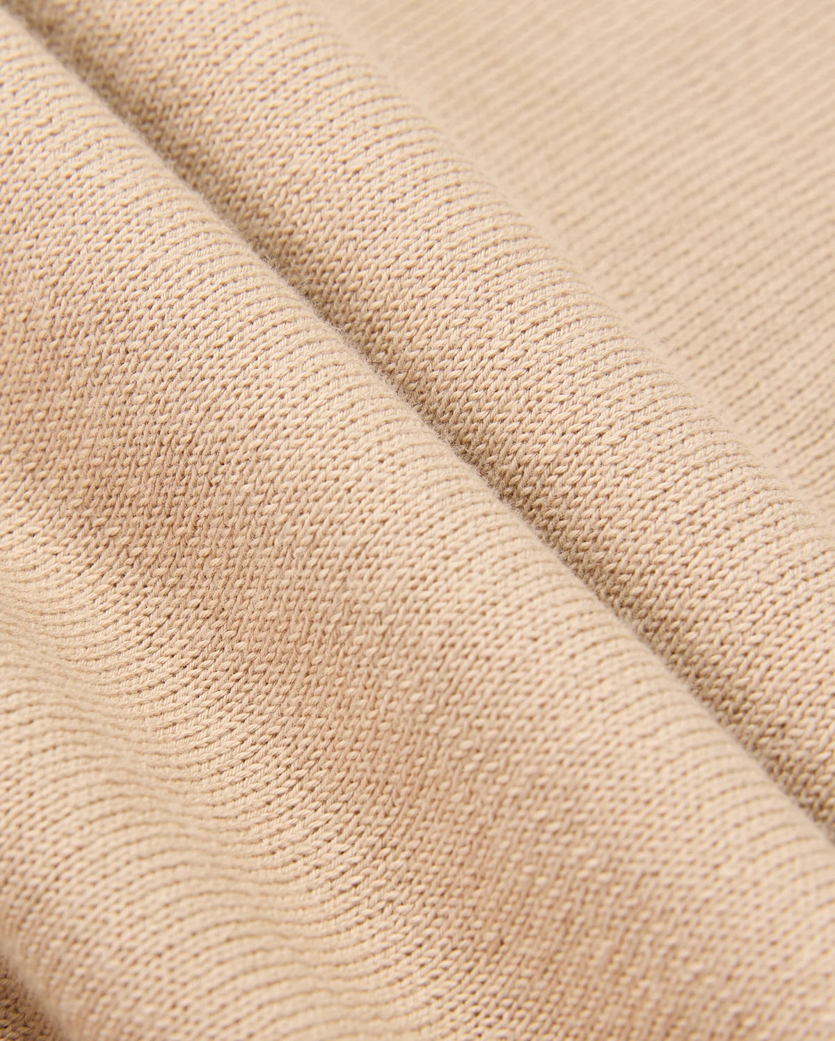 Here's a close-up of the MENS CORY CHAINSTITCH COTTON SWEATER by Psycho Bunny. This beige sweater features a lightweight cotton fabric with a textured, woven pattern, draped in gentle folds to highlight its soft and flexible nature.