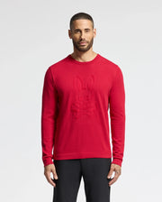 A short-haired, bearded person wears a Psycho Bunny MENS COORY CHAINSTITCH COTTON SWEATER featuring a vibrant skull and crossbones with bunny ears. The chainstitch embroidery adds texture. They're against a neutral background, paired with black pants.