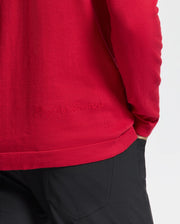 A person wearing a Psycho Bunny MENS COORY CHAINSTITCH COTTON SWEATER in red, paired with black pants in a casual setting.