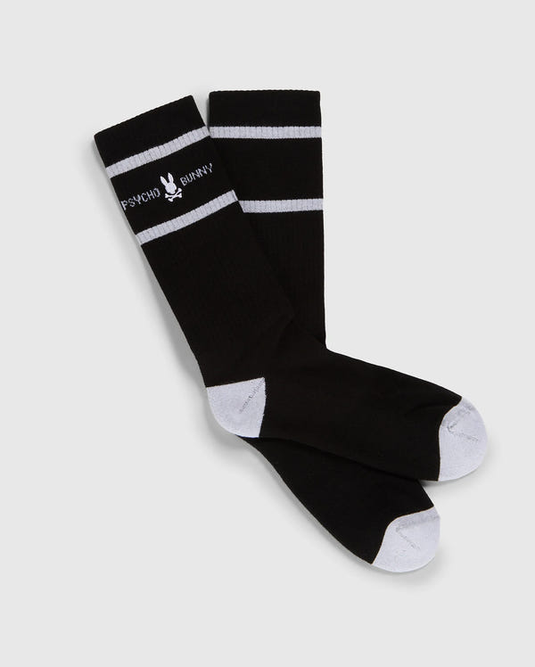 A pair of black knee-high Psycho Bunny fashion socks with white toe and heel patches and two white horizontal stripes near the top, featuring the text "PSYCHO BUNNY" in white.