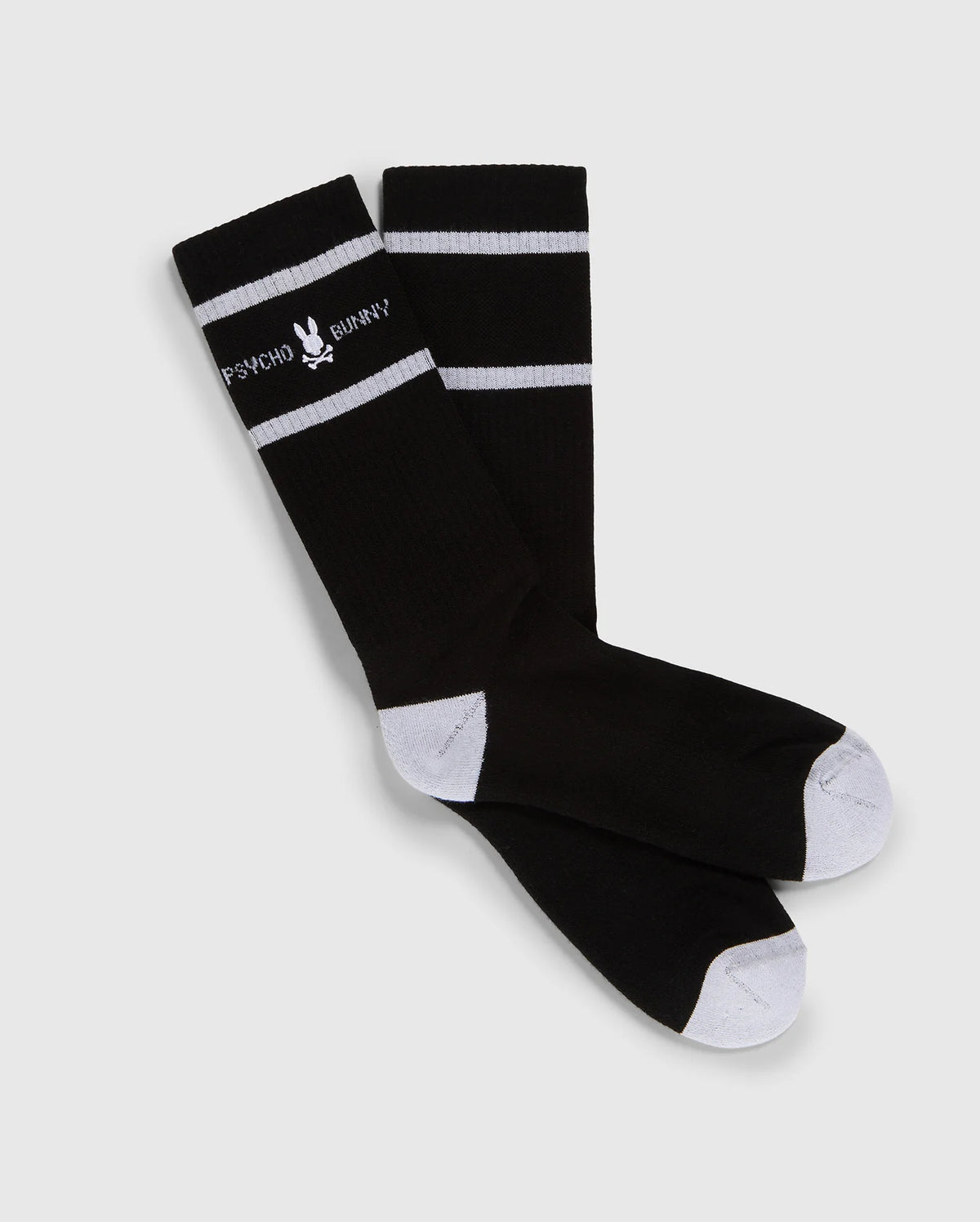 A pair of black knee-high Psycho Bunny fashion socks with white toe and heel patches and two white horizontal stripes near the top, featuring the text "PSYCHO BUNNY" in white.