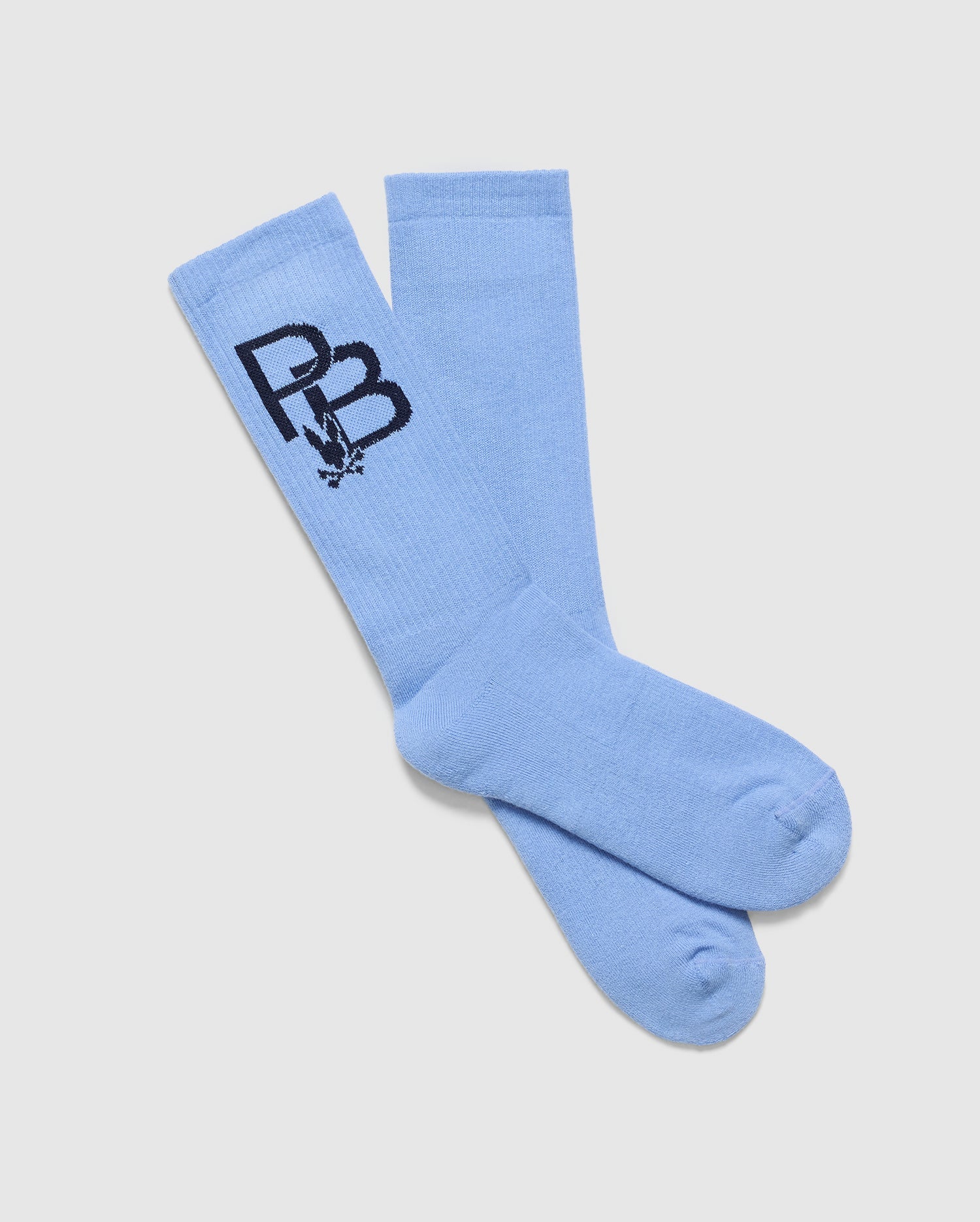 The MENS PB SPORT SOCK - B6F501F200 by Psycho Bunny are light blue socks made of Pima cotton, adorned with a black "PB" logo and small graphics. They cross over each other on a white background, merging comfort and sporty style effortlessly.